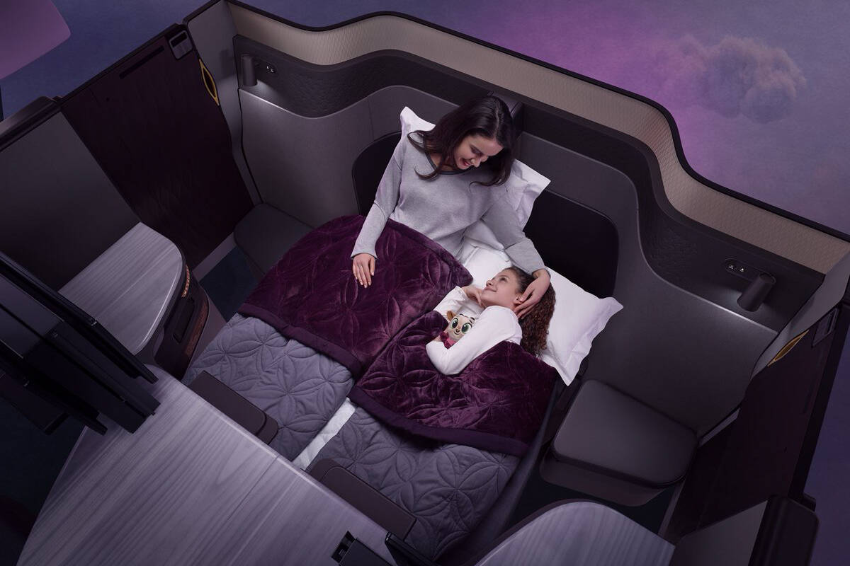 A woman is sleeping in a bed on a plane.