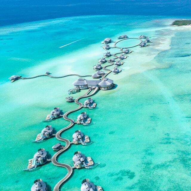 An aerial view of a resort in the middle of the ocean.