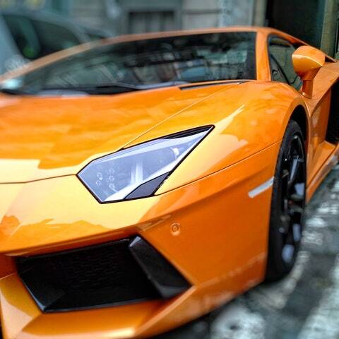 An orange sports car is parked in front of a building.