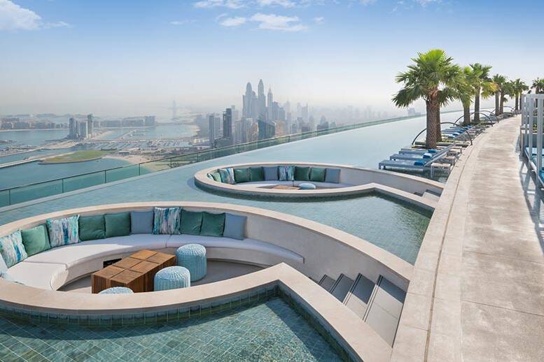 A rooftop pool overlooking the city of dubai.