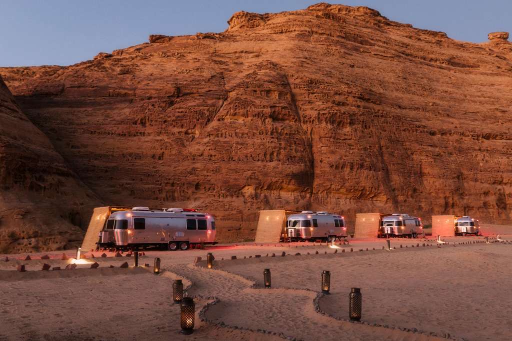 A group of rvs parked in the desert at dusk.