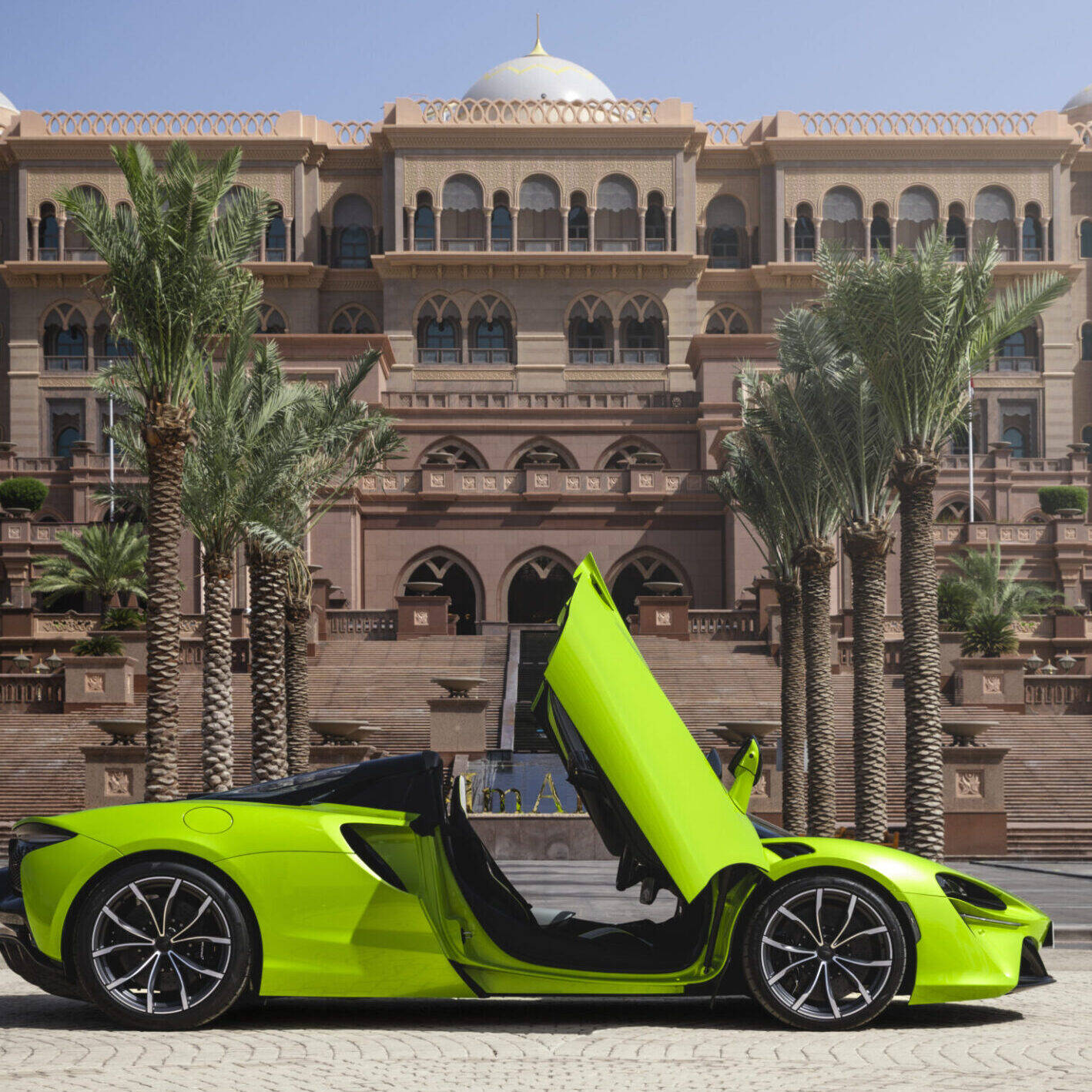 Green sports car parked in front of a hotel.