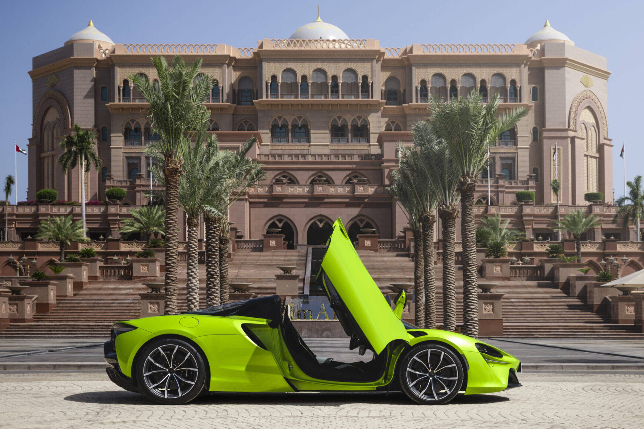 Green sports car parked in front of a hotel.