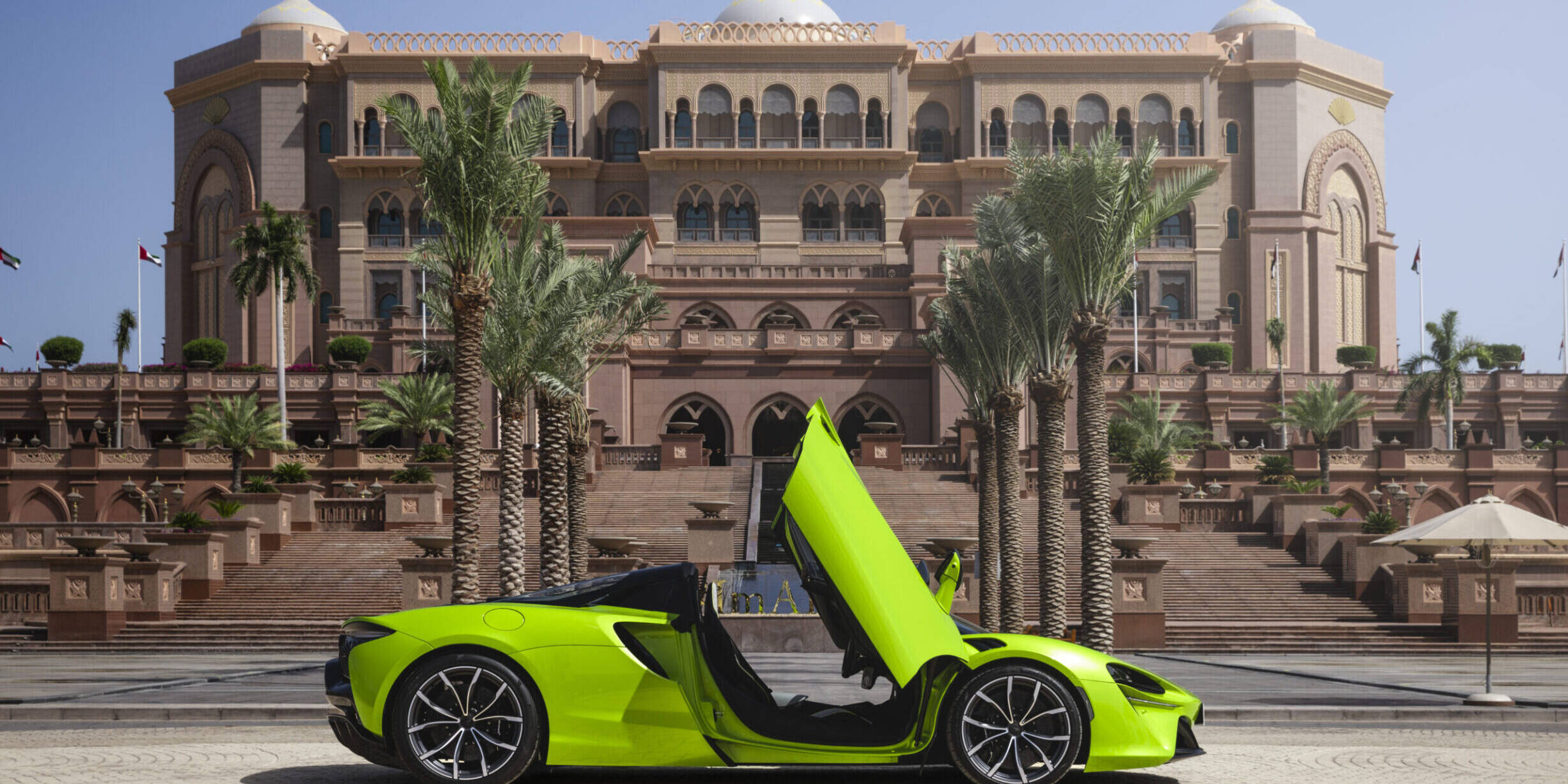 Green sports car parked in front of a hotel.